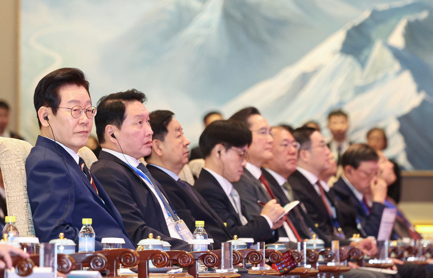 President Lee Jae Myung, left, listens at the Korea-China business forum held at the Diaoyutai State Guesthouse in Beijing on Jan. 5 during a state visit to the country. The event was attended by the heads of Korea’s top conglomerates including SK Group Chairman Chey Tae-won, second from left, Samsung Electronics Executive Chairman Lee Jae-yong, fifth from left, Hyundai Motor Group Executive Chair Euisun Chung, sixth from left, and LG Group Chairman Koo Kwang-mo, seventh from left. [JOINT PRESS CORPS]