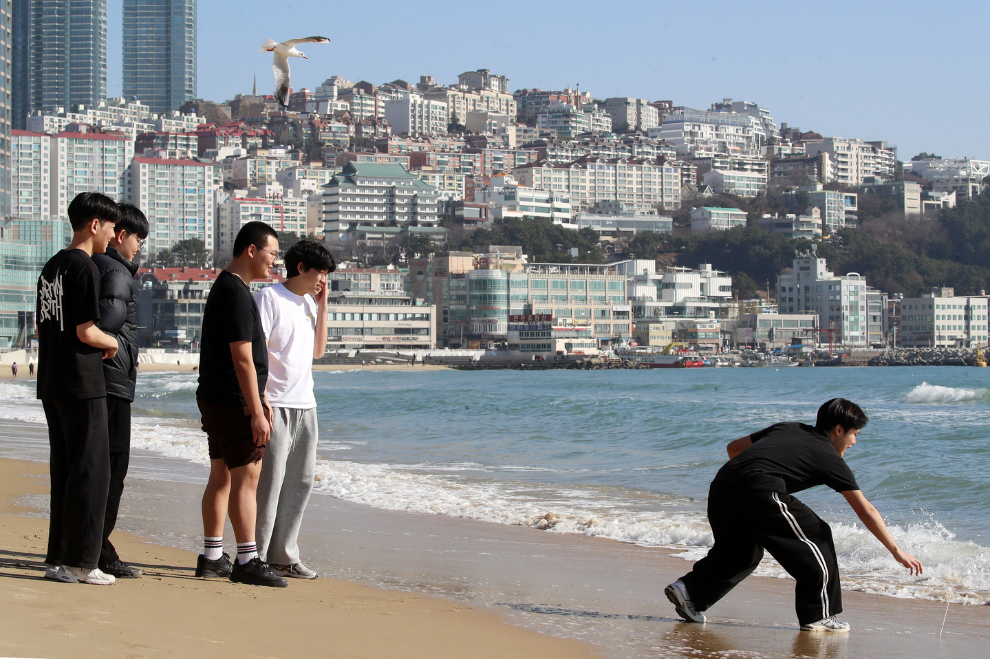 People wearing short sleeves walk along Haeundae Beach in Busan on Jan. 16, enjoying the mild weather. [NEWS1]
