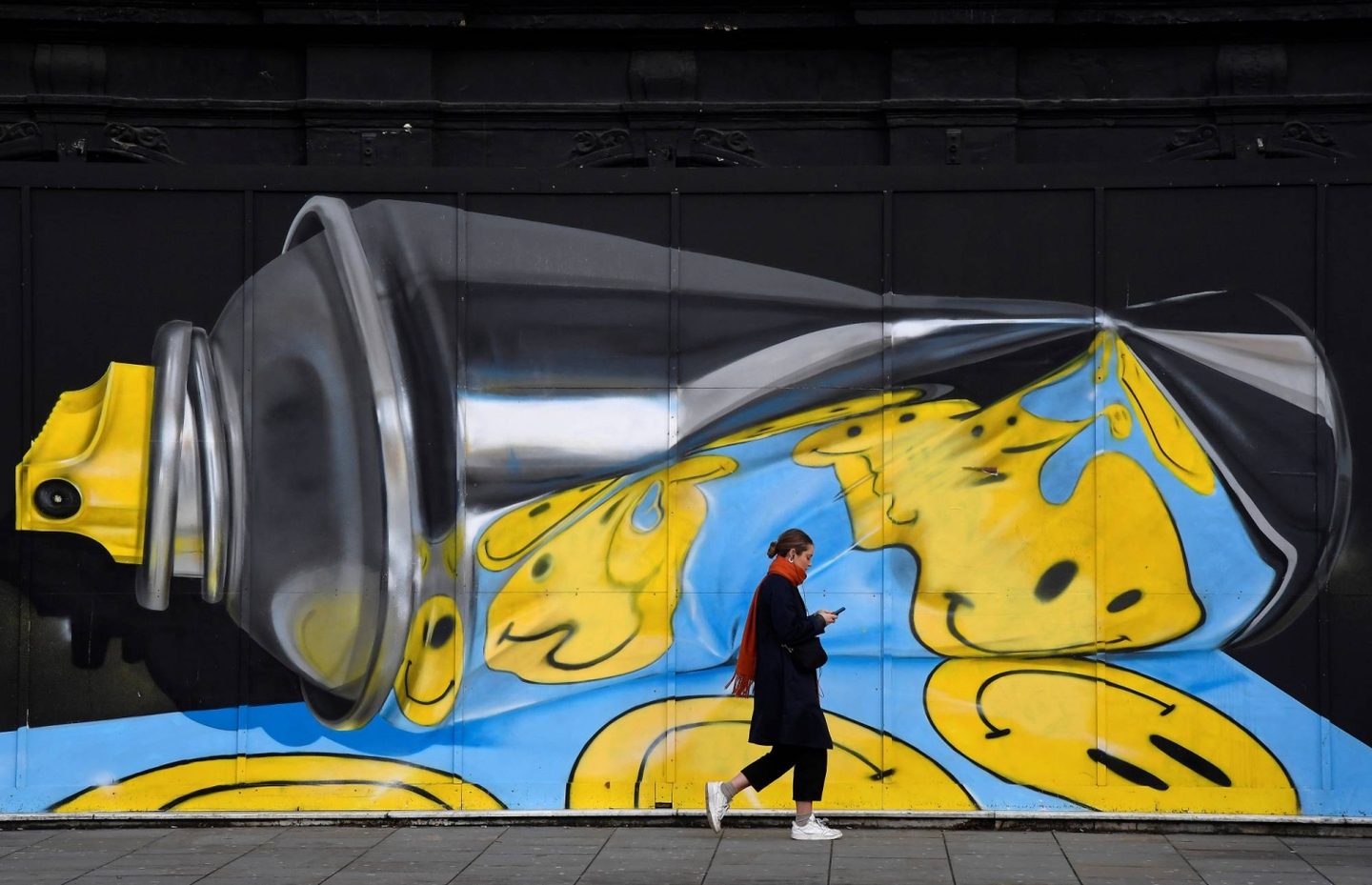 A woman views her phone as she walks past street art on a wall in London, on December 18, 2019.  [REUTERS/YONHAP]