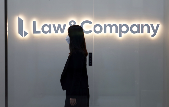 A pedestrian passes by the Low&Company sign displayed on its building on Feb. 23, 2023. [YONHAP]