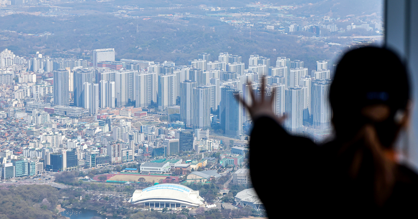 A person gestures toward apartment buildings from a skyscraper in southern Seoul on April 8. [NEWS1] 