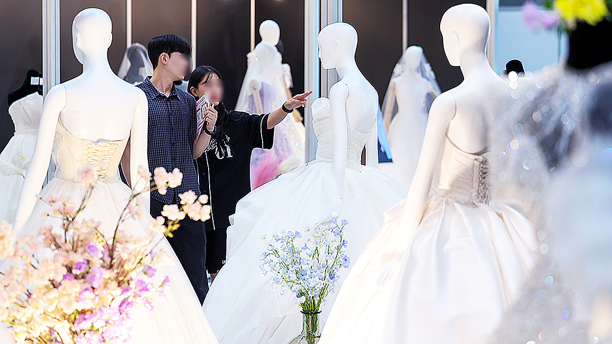 Visitors at a wedding fair at Coex in Gangnam District, southern Seoul, look at wedding dresses on July 6, 2025. [NEWS1]