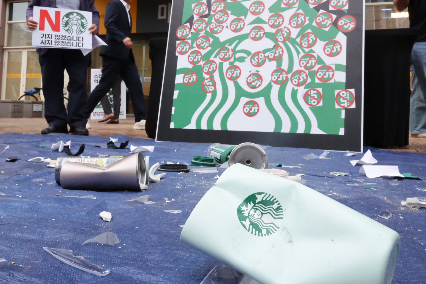 Starbucks tumblers and cups lay on the ground, broken and dented, at a press conference condemning Starbucks Korea in front of the E-Mart Gwangju branch on May 21. [YONHAP]